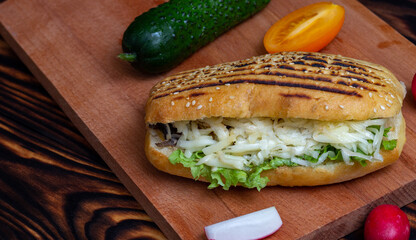 sandwich on a cutting board on a table with vegetables