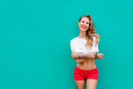 Fun and colorful. Young pretty happy woman in shorts posing against green wall.