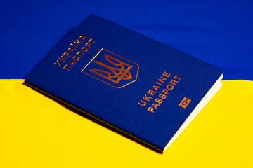 Ukrainian biometric passport on blue yellow flag of ukraine. ID document of identification of the person, citizenship of Ukraine. Concept of tourism, emigration, refugees due to the war 2022. Close up