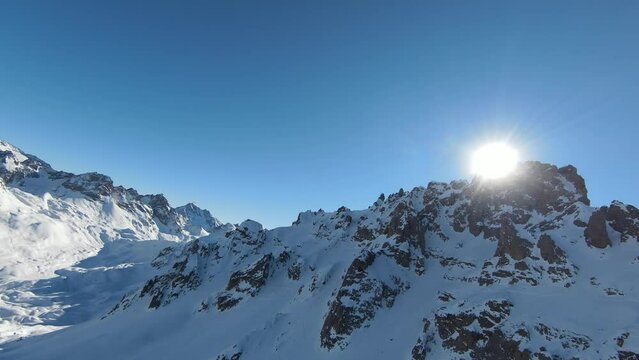 Aerial view sport FPV drone raising up top of mount. Beautiful peaks of the alps covered with snow cover