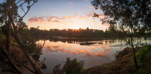 Panoramic riverside sunrise with cloud reflections