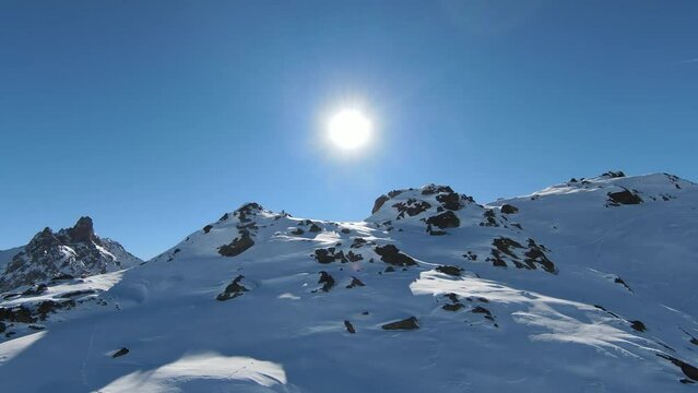 Aerial view sport FPV drone raising up top of mount. Beautiful peaks of the alps covered with snow cover