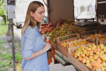 young woman chooses fruits at street shop