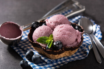 Blueberry ice cream scoops with waffle on black background