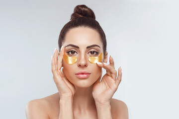 Woman applying golden eye patches. Close up portrait girl. Young woman applying golden collagen...