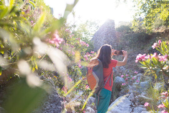 A woman takes a photo of the sights on a smartphone, park with oleander flowers