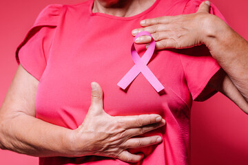 Woman attaches pink ribbon in National cancer survivor day.