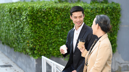 Shot of mature businesswoman and businessman having a discussion while walking at modern office district