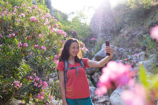 A woman takes a selfie against the background of a landmark, park with oleander flowers