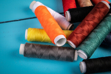 Thread spools on  blue wooden background. Fashion and hobby