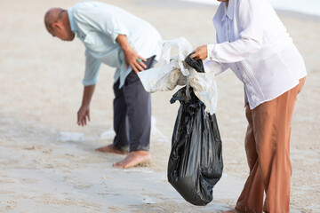 volunteer keeping and picking trash into garbage bag on the beach