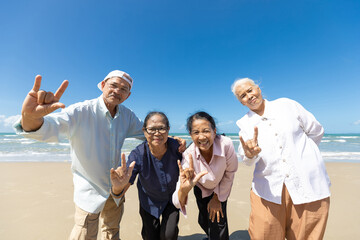 portrait senior man and women with rock and roll hand gesture symbol pose on the beach