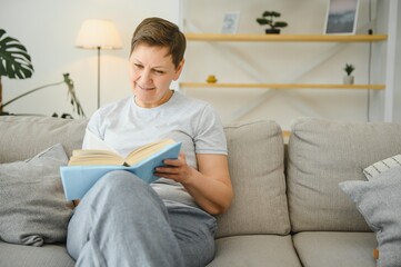 Fototapeta na wymiar woman in home sitting on sofa reading book.