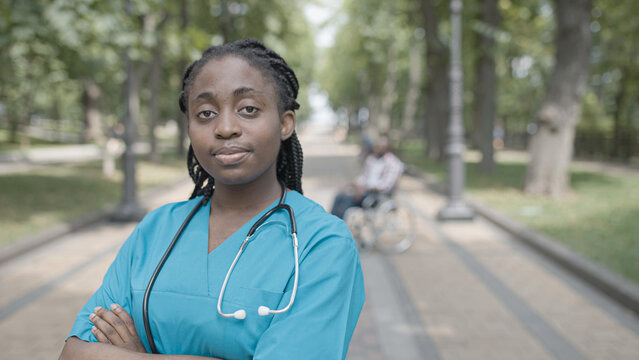 Confident female doctor crossing arms on chest and smiling on camera in park - Powered by Adobe