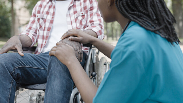 Female nurse supporting male patient in wheelchair, communication, recovery