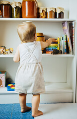First Books for Newborns and Babies. Cute little baby toddler girl with colorful book at home.