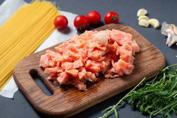 Cooking spaghetti with salmon and vegetables. Raw ingredients lie on a gray background.
