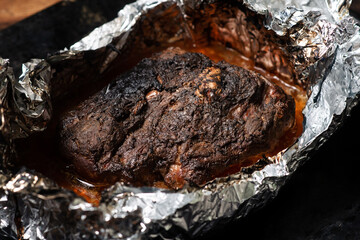 A piece of meat baked in the oven in foil. Home cooking.