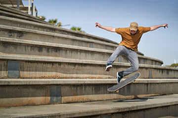 A young man doing an ollie 360 flip with his skateboard on some bleachers - Powered by Adobe