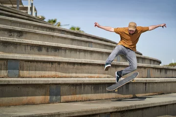 Fototapeten A young man doing an ollie 360 flip with his skateboard on some bleachers © Retamosa