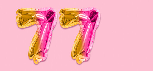 Rainbow foil balloon number, digit seventy seven on a pink background. Birthday greeting card with inscription 77. Top view. Numerical digit. Celebration event, template. Banner