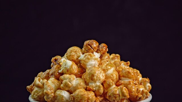 Coffee taste popcorns rotating into the bowl on black background close up. Caramel popcorn. Healthy food for morning breakfast. Healthy breakfast concept. High quality 4k footage