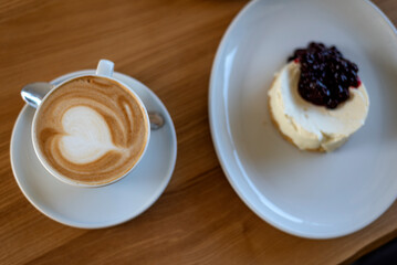 White cup of latte or cappuccino coffee and dessert on wooden table. Top view. Coffee and sweets in cafe or pastry shop.