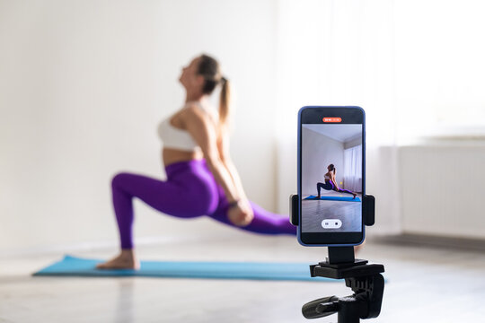 woman practicing yoga poses stretching in front of phone camera sport blogger teacher yoga online