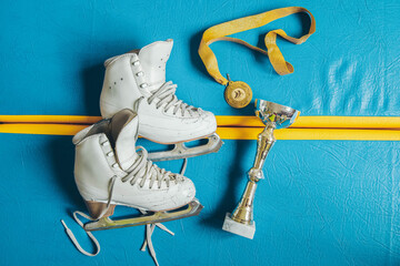 White skates for figure skating, winner's cup, gold medal.