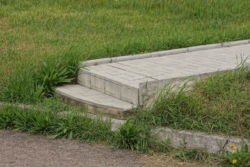 alley of gray white paving slabs along the green grass on street