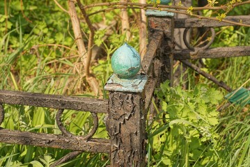 part of an black iron old decorative fence with a sharp one detail with a tip of metal overgrown with green grass