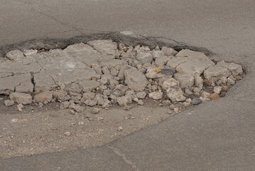 one big pothole on the gray asphalt road on the street