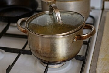 a one big gray dirty metal saucepan with a lid on the stove