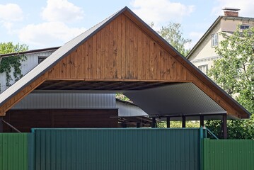 brown wooden roof covering over a private courtyard and green metal gates on the street