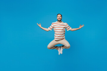 Full body young smiling man 20s wear orange striped t-shirt hold spreading hands in yoga om aum...