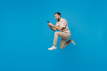 Full body side view young excited fun cool overjoyed man 20s in orange striped t-shirt jump high...