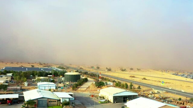 Large sandstorm sweeps across the dry yellow landscape of Israel's Southen Arava as a car pulls out of the storm on the highway. Drone dolley shot