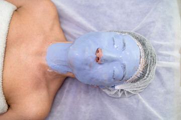Beautician procedures - dermatolog applying face mask to young woman