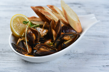 mussels in the shell with sauce, croutons and lemon