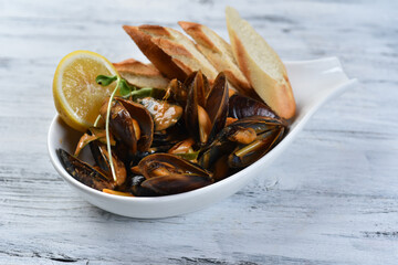 mussels in the shell with sauce, croutons and lemon