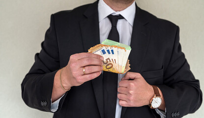 man in suit with good taste holds euro banknotes for big purchase.