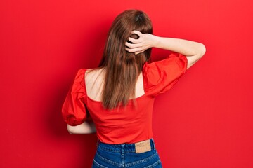 Redhead young woman wearing casual red t shirt backwards thinking about doubt with hand on head