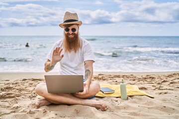 Young redhead man having video call using laptop at the beach.