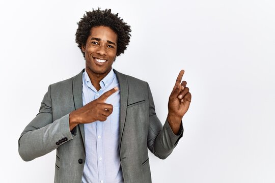 Young african american man wearing business jacket over isolated white background smiling and looking at the camera pointing with two hands and fingers to the side.