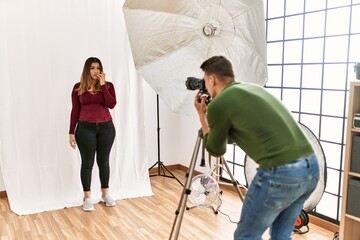 Young woman at photography studio looking stressed and nervous with hands on mouth biting nails. anxiety problem.