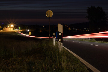 Landstraße mit Lichtspuren von Fahrzeugen.