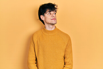 Obraz premium Handsome hipster young man wearing casual yellow sweater smiling looking to the side and staring away thinking.