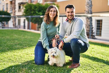 Man and woman posing with dog at park
