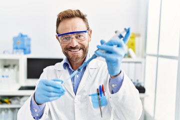 Middle age hispanic man wearing scientist uniform working at laboratory