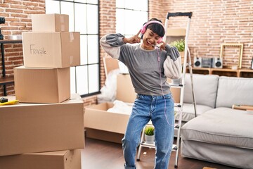 Young woman listening to music and dancing at new home